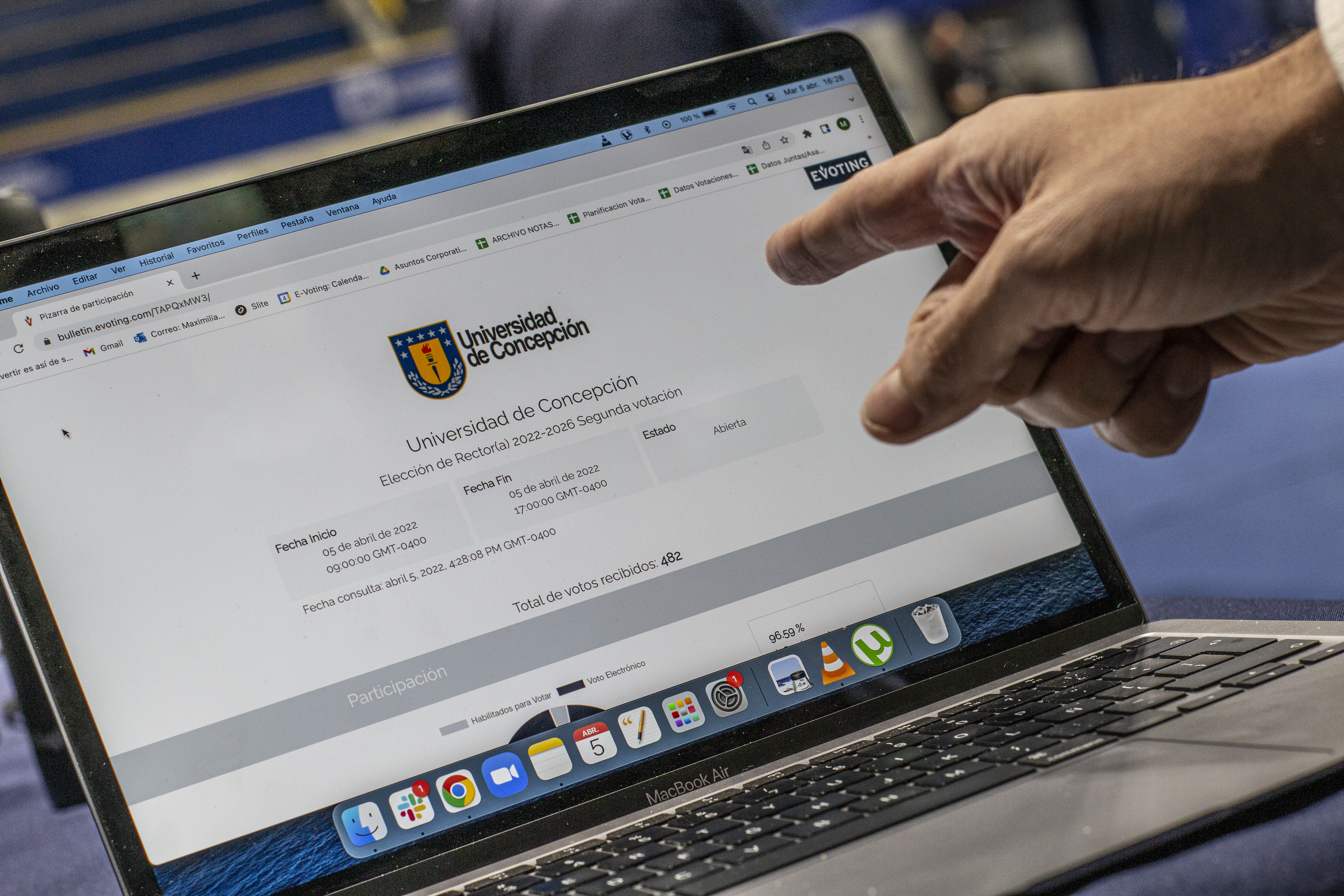 Pantalla de computador con votación de EVoting en la Universidad de Concepción, con mano apuntando a ella