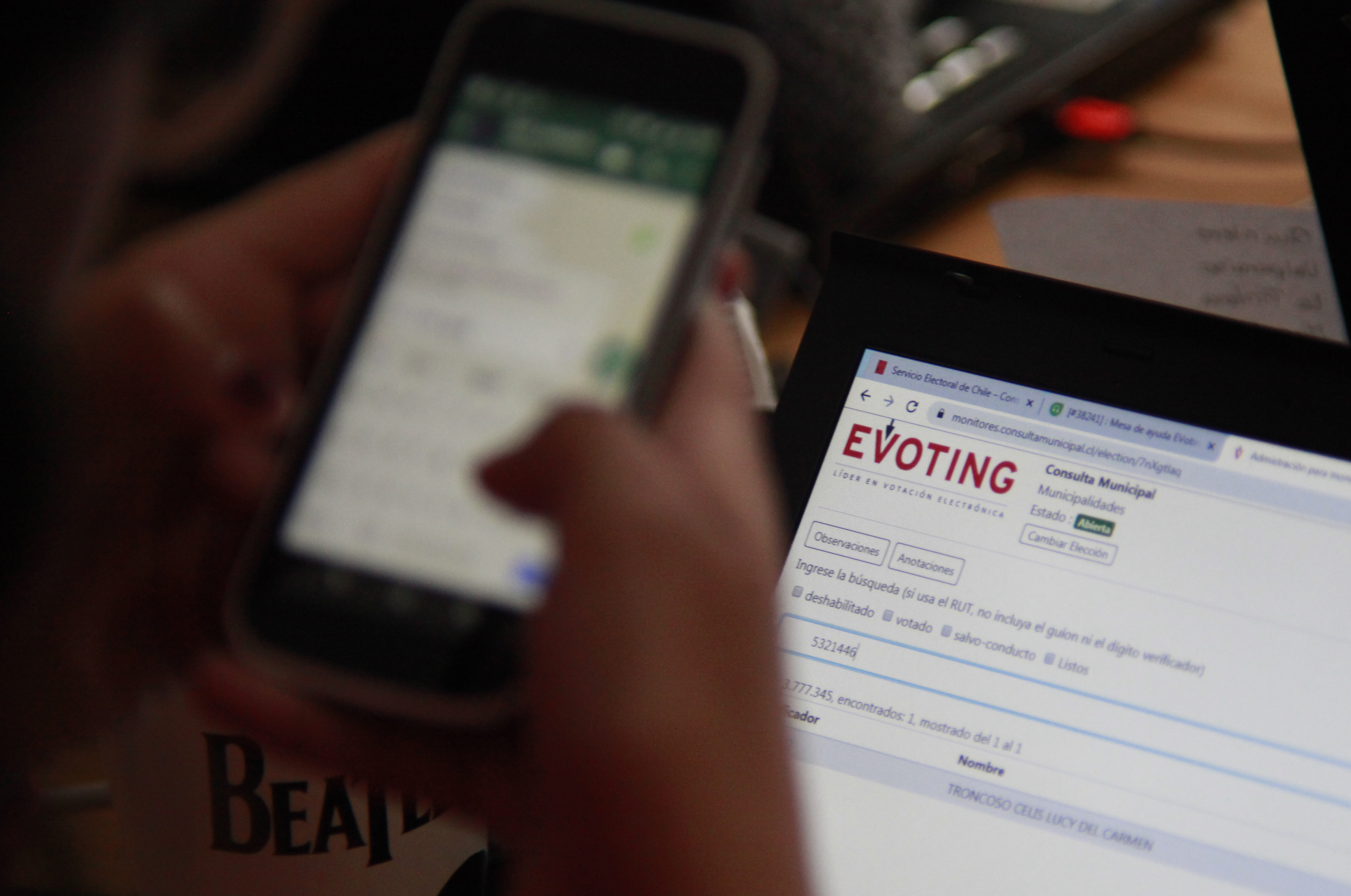 Pantalla de teléfono frente a pantalla de computador que muestra la plataforma de votaciones electrónicas de EVoting